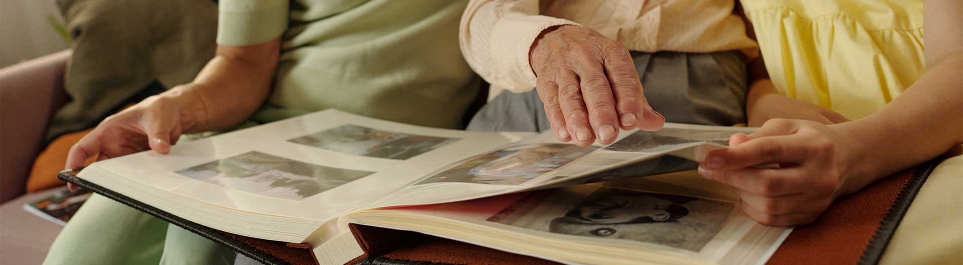 close up of family sitting on couch, looking through a photo album, telling stories of times past