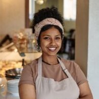 photo of dining room employee, wearing an apron, smiling